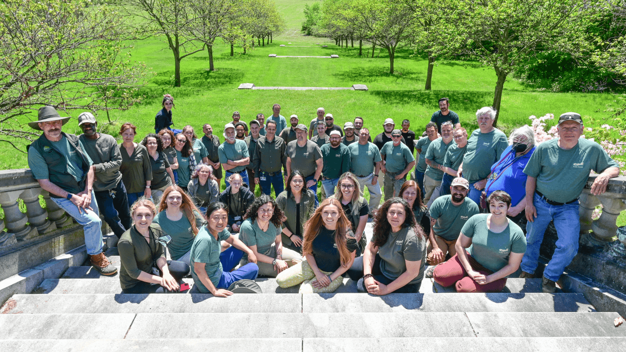 Group picture of Duke Farms staff sitting and standing on a wide staircase and smiling at the camera.