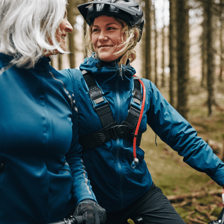 Picture of a person on a bicycle with a helmet on, smiling at another person.