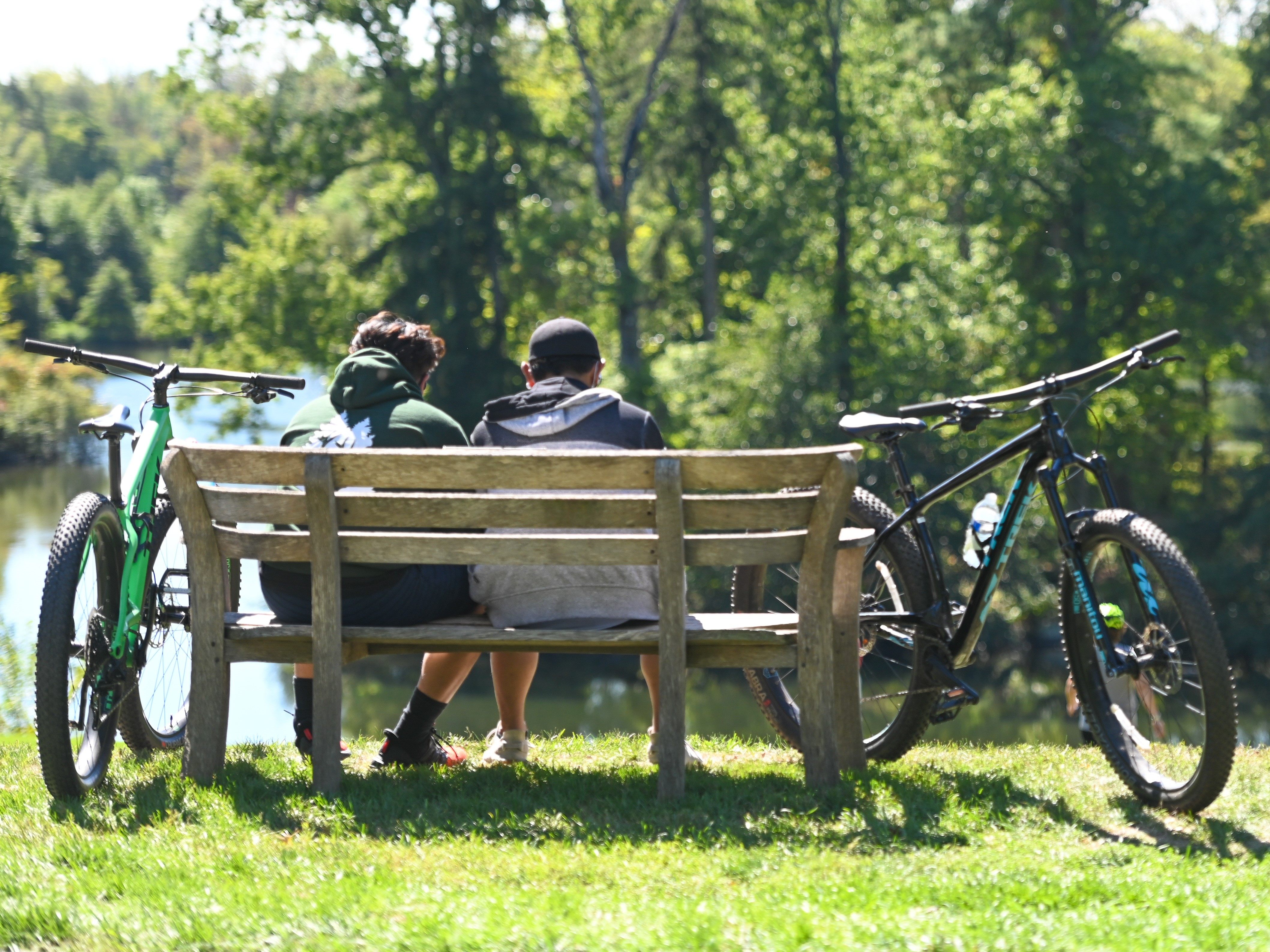 Two people sitting on a bench, with their bikes beside them.